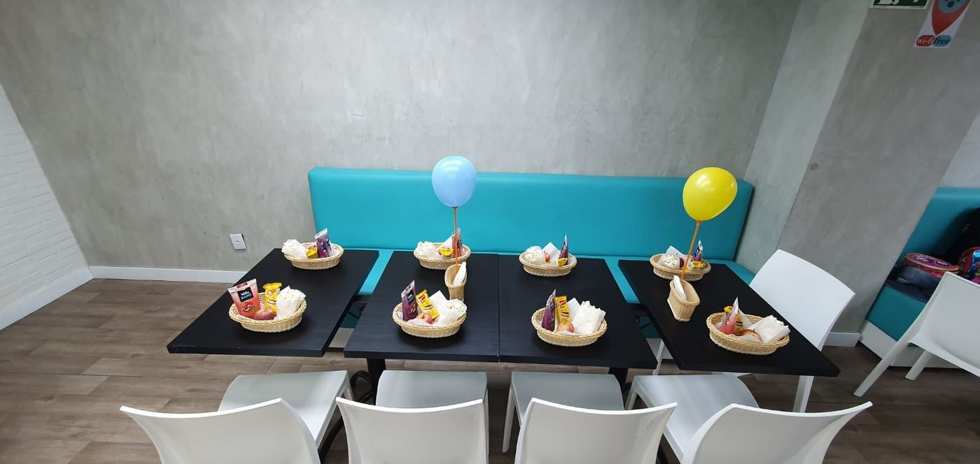 Mesas do salão com cestinhas de lanche e balões