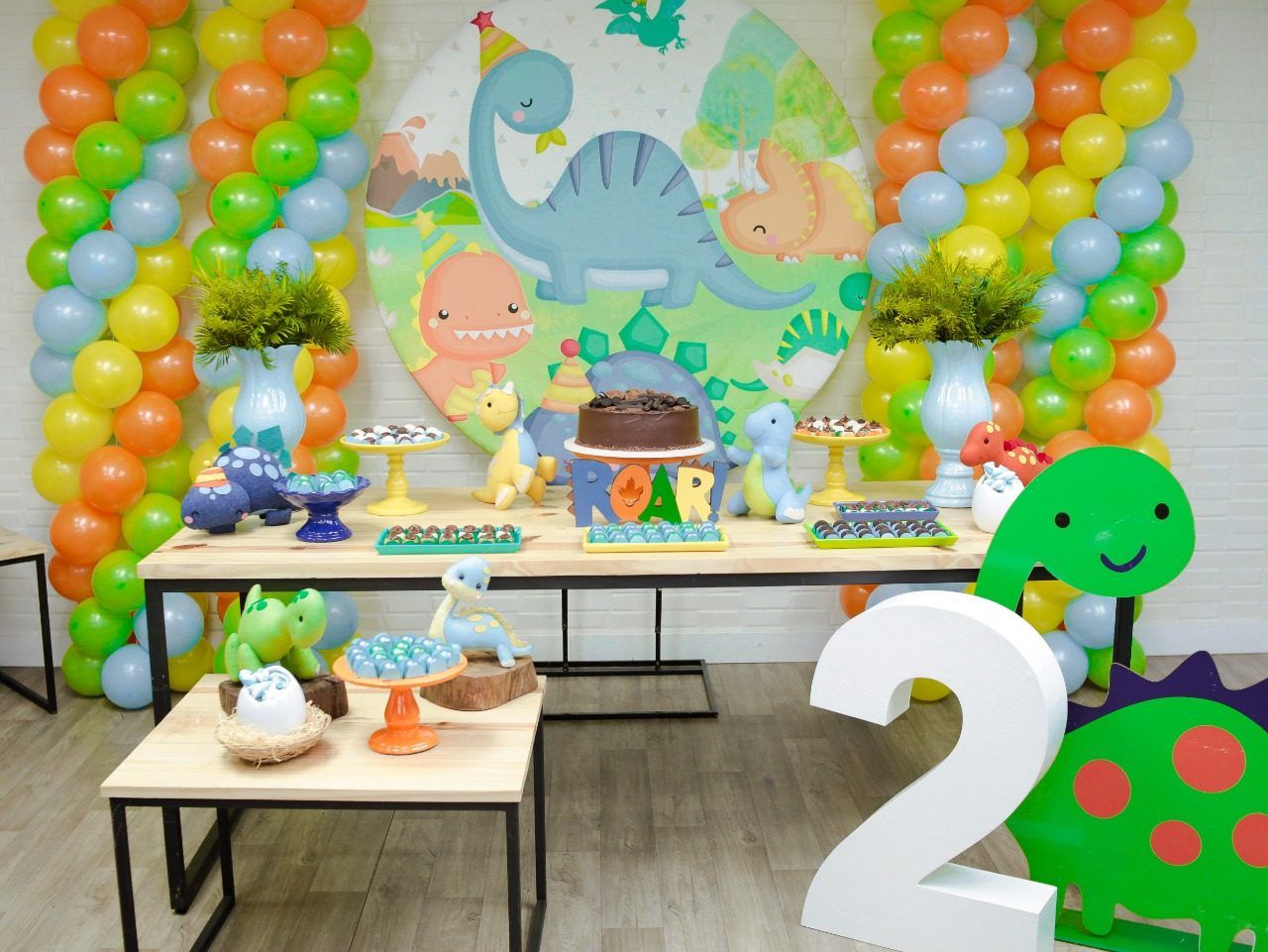 Mesa de festa com tema de dinossauros e balões coloridos