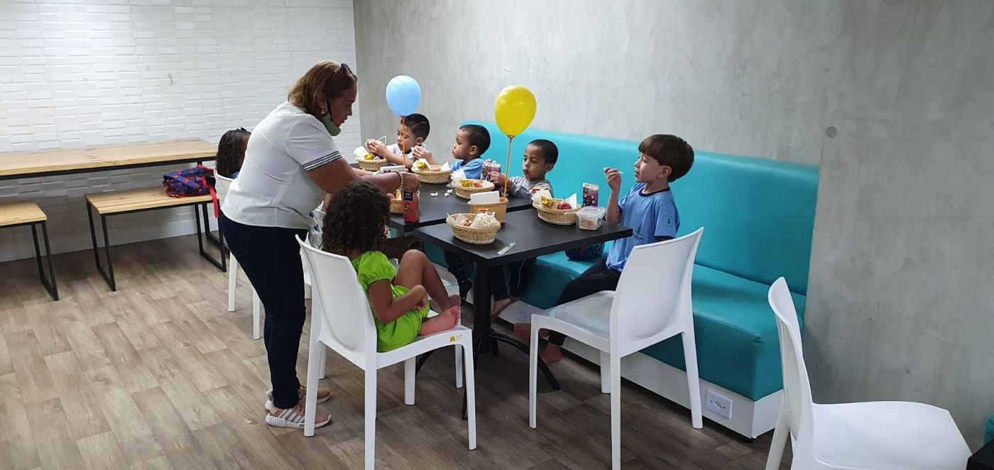 Professora acompanhando as crianças na mesa do lanche